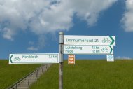 Drei Schilder aus dem Knotenpunktsystem, mit den Pfeilrichtungen Norddeich, Dornumersiel und Lütetsburg / Hage