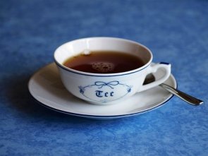 Auf dem Bild sieht man eine Tasse Ostfriesentee. Auf der weißen Tasse steht in blauer Schrift "Tee".