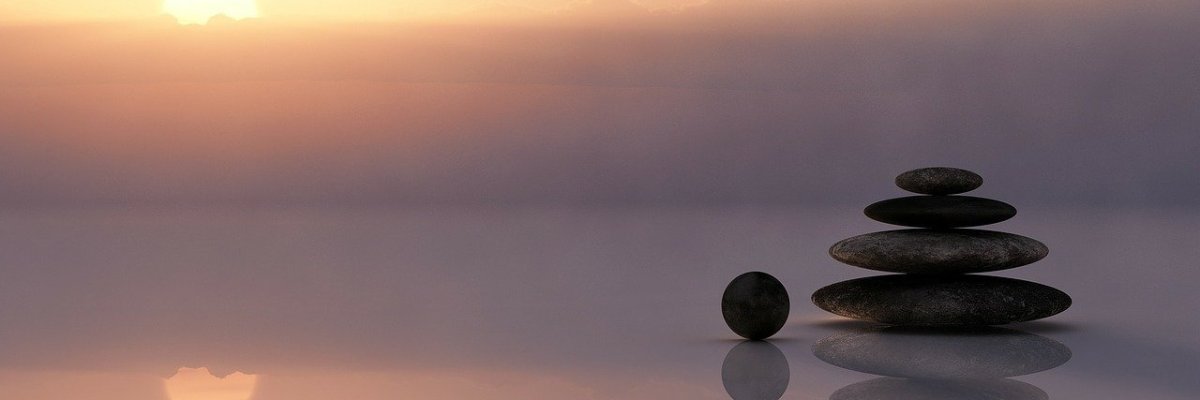 Auf dem Bild ist ein Farbverlauf in den Farben vom Sonnenuntergang und auf der rechten Seite sind schwarze Steine gestapelt.